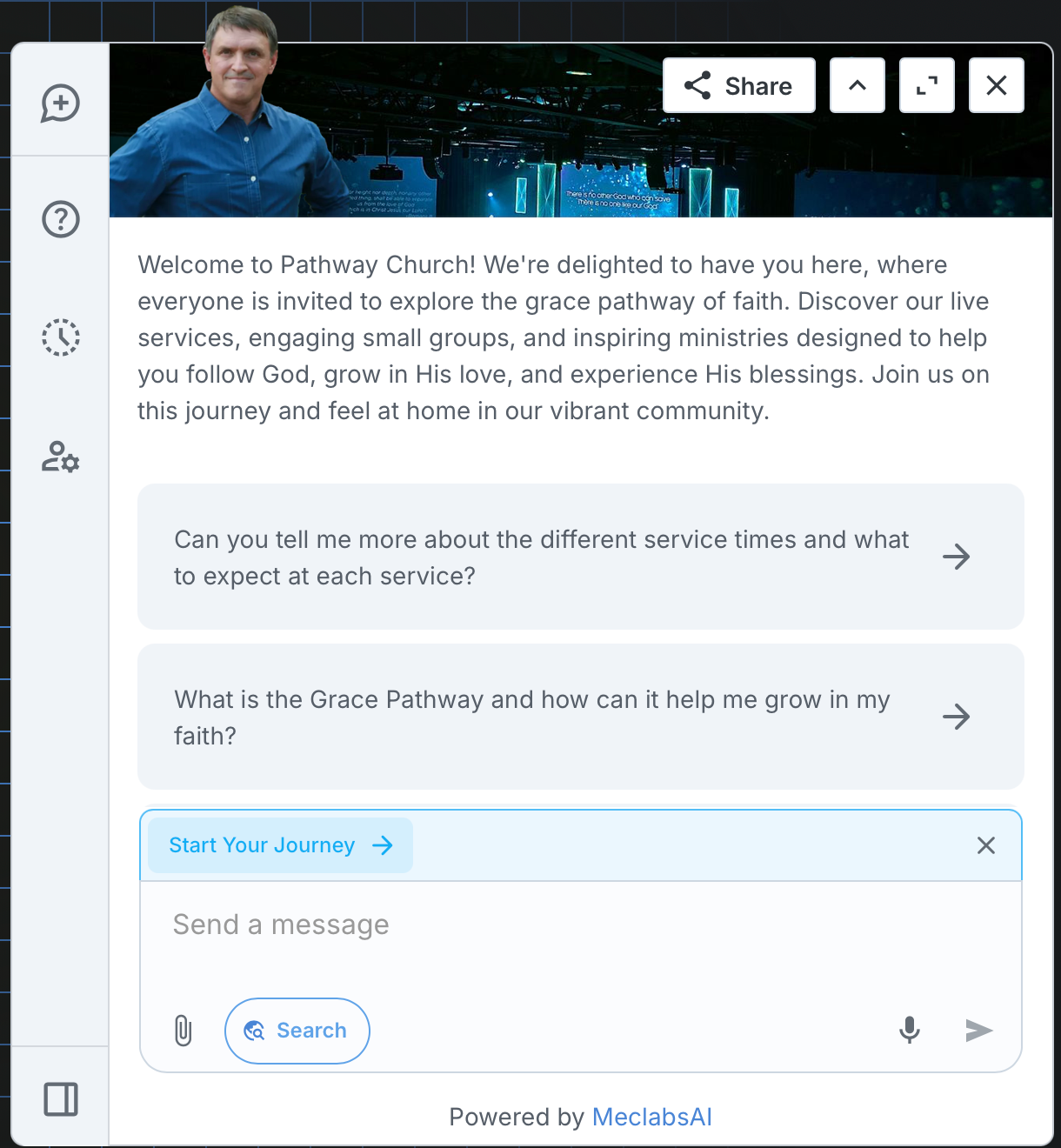 A man in a blue shirt is standing in front of a computer screen.