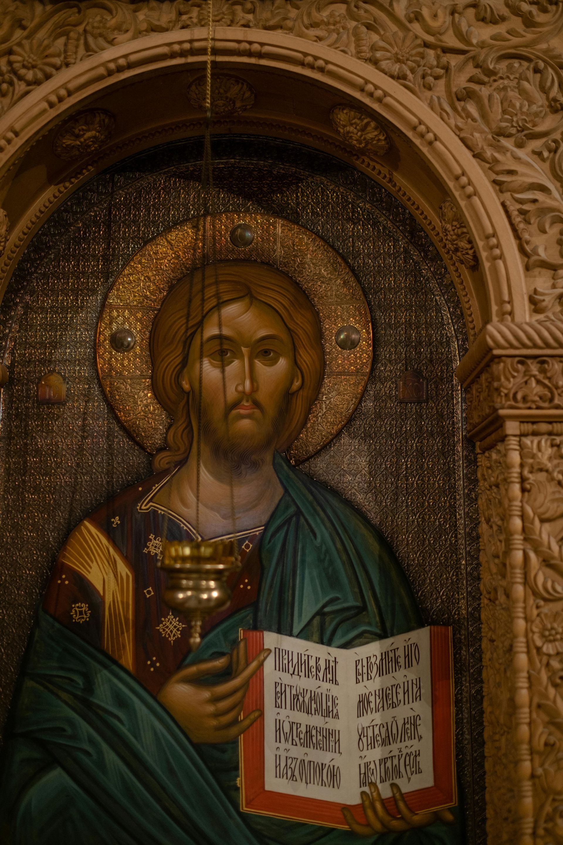 A painting of jesus holding a book and a cup