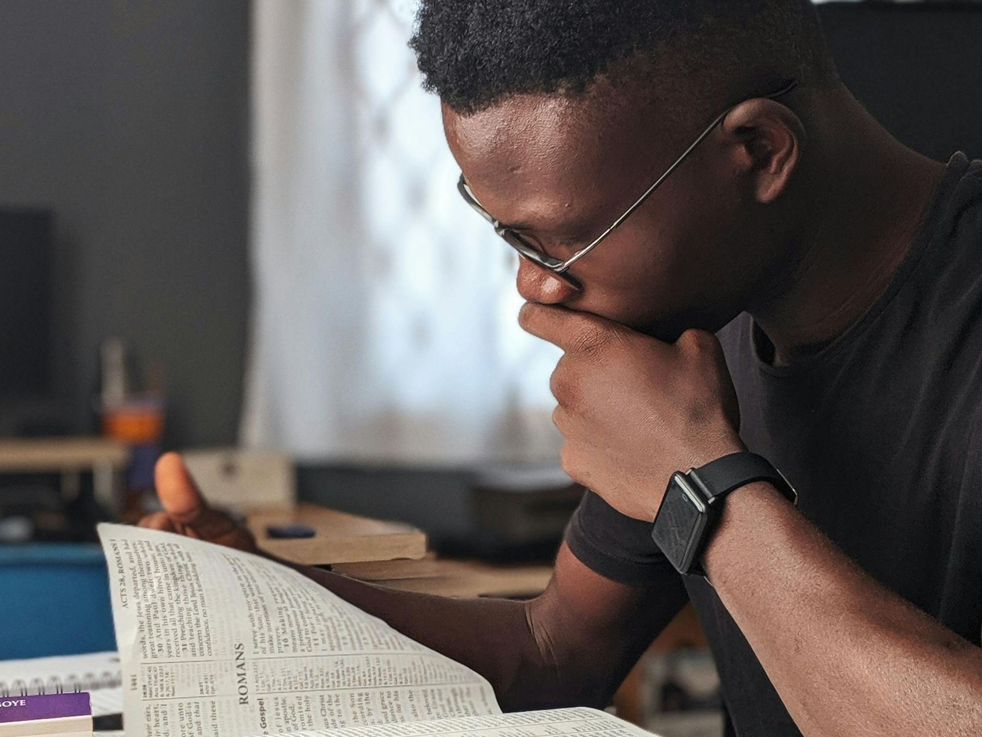 A man wearing glasses is reading a book.