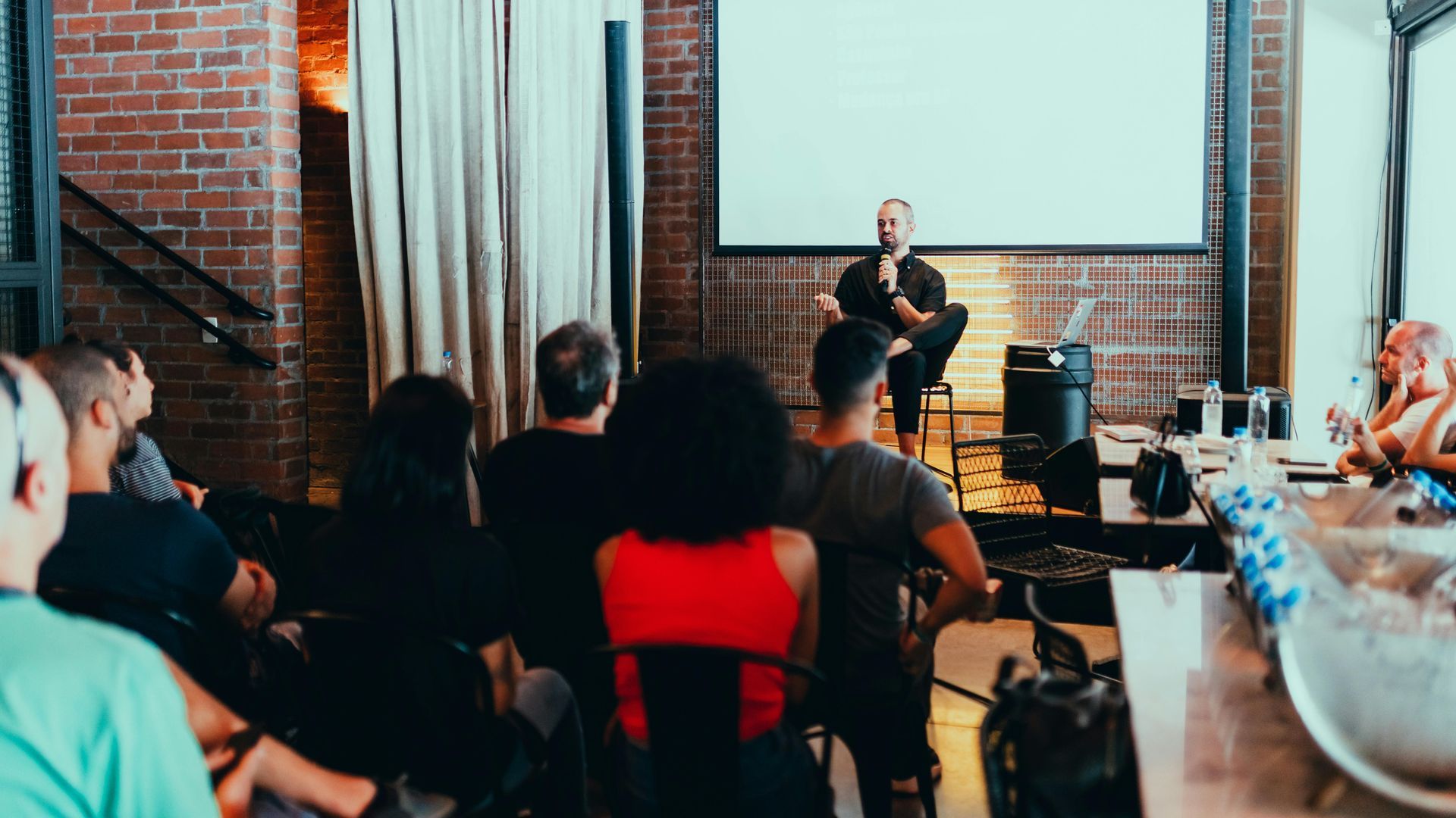 A group of people are sitting in front of a projector screen.