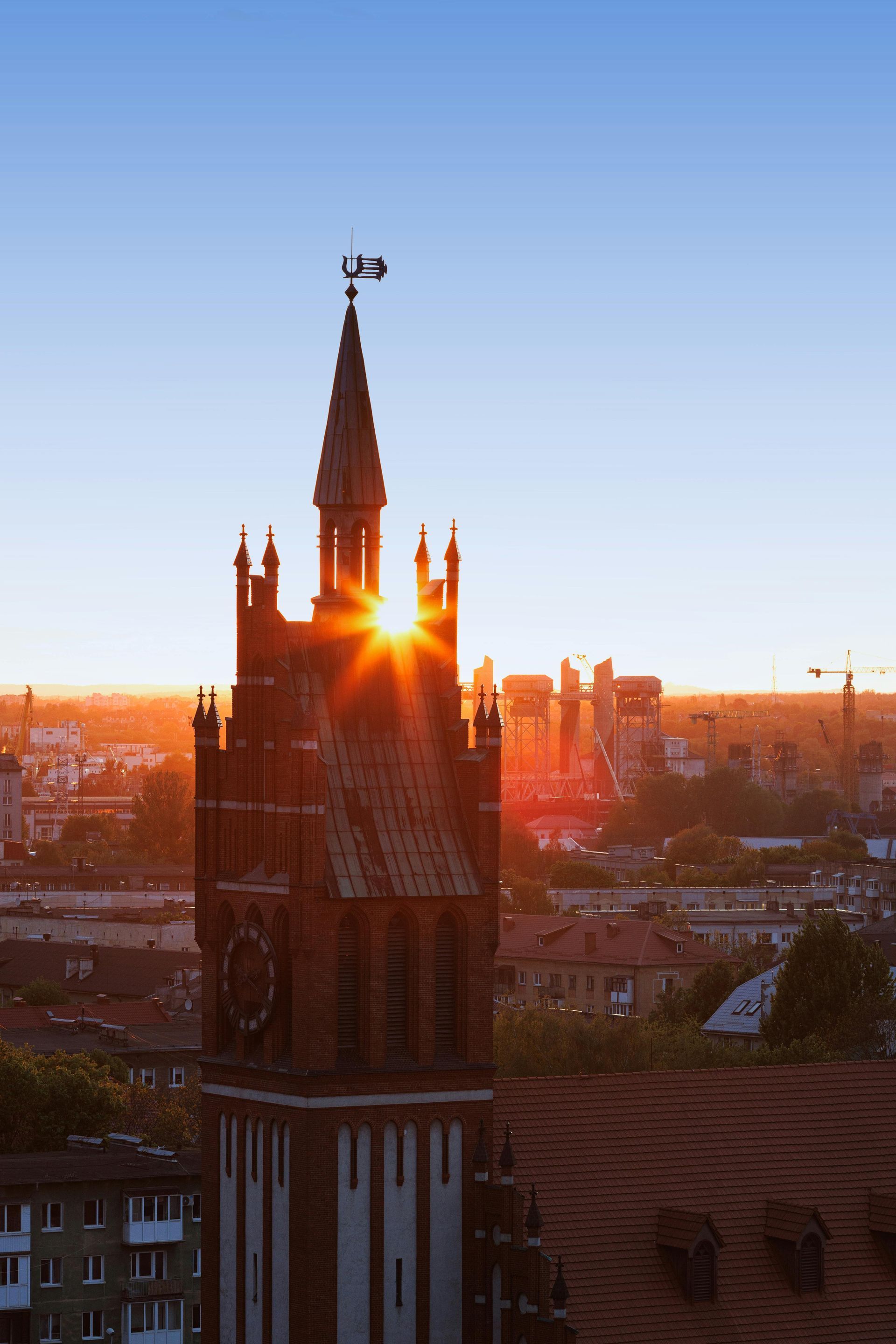 Sunrise over a brick tower in a city, sunburst effect, with blue sky.