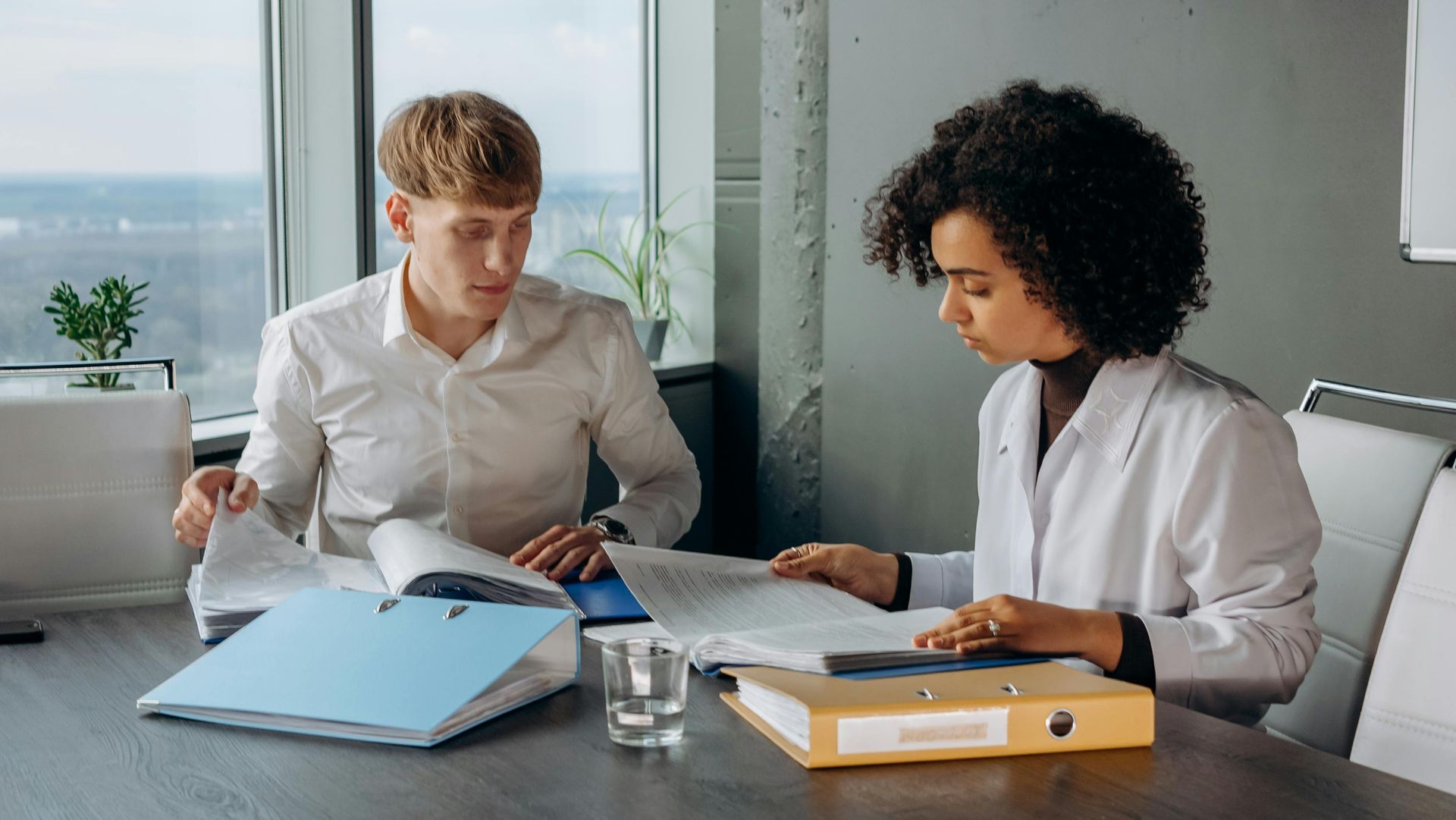 A man and a woman are sitting at a table looking at papers.