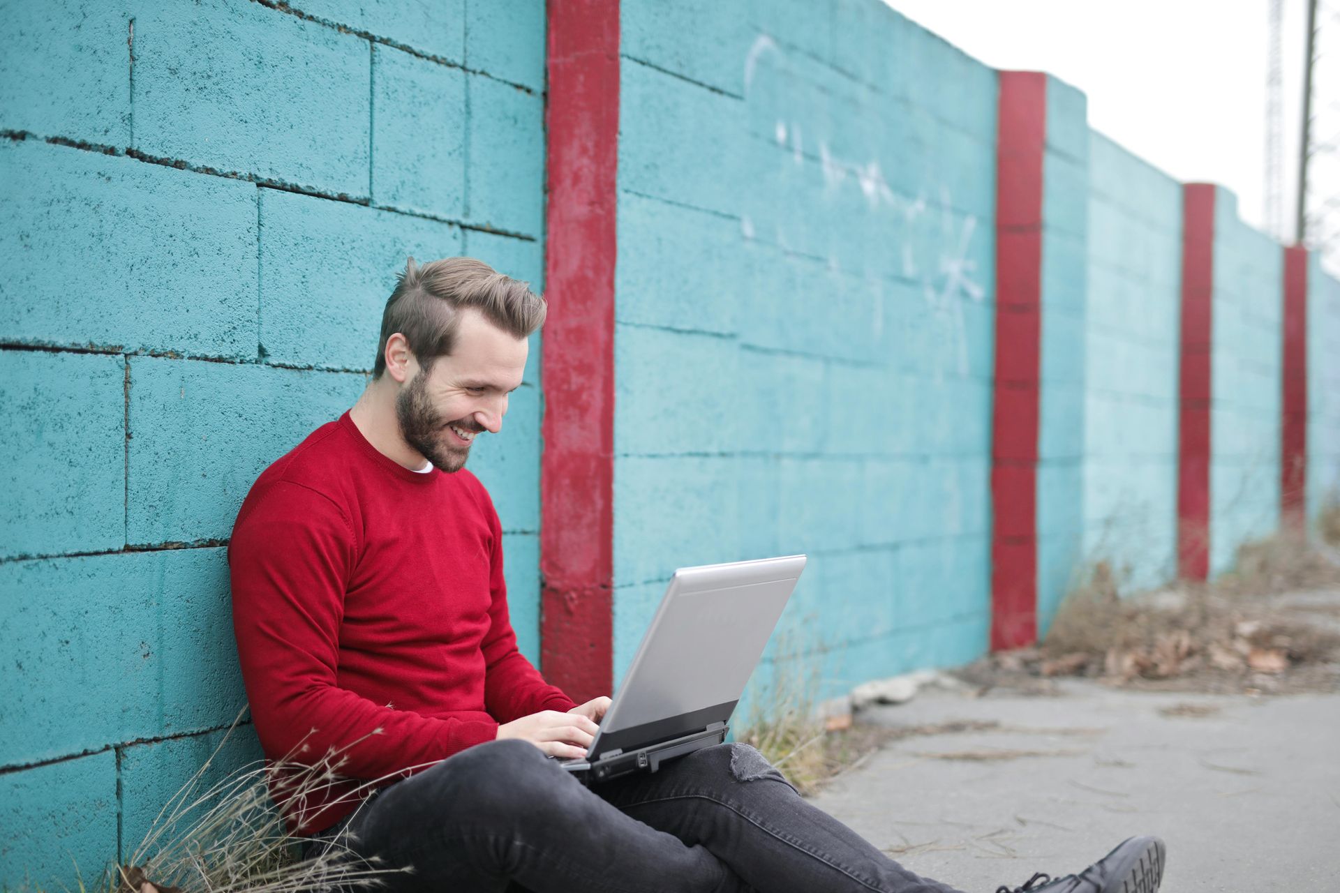 A man is sitting on the ground using a laptop computer.