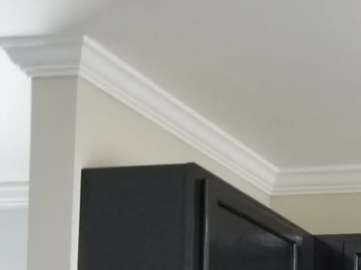 White crown molding on wall and ceiling above dark cabinets.