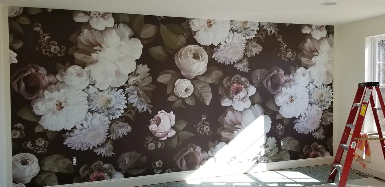 Floral wallpaper covers a wall. A red ladder stands near a window. Sunlight streams in.