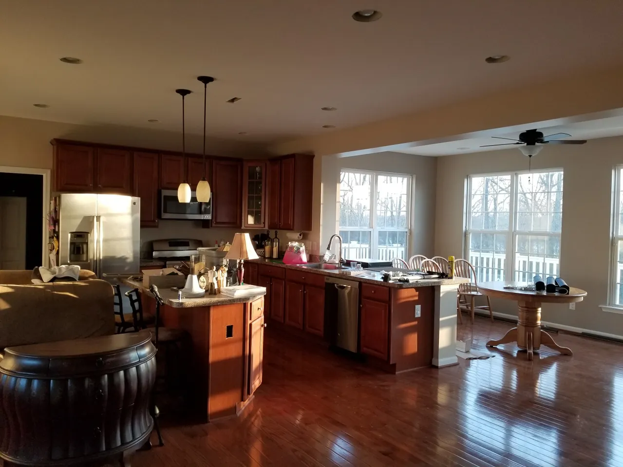 Spacious kitchen with wood cabinets, island, and dining area bathed in warm sunlight.