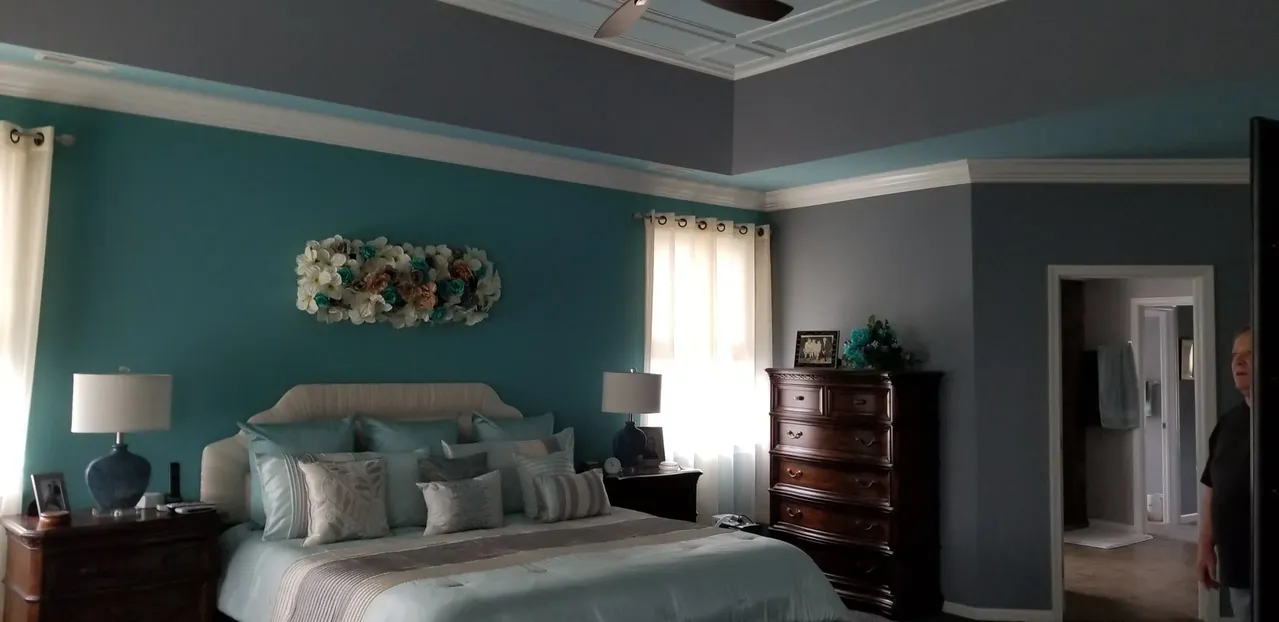 Bedroom with teal walls, a bed with light blue bedding, and a dark brown dresser.