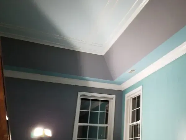 Room with teal and gray walls, white trim, and two windows.