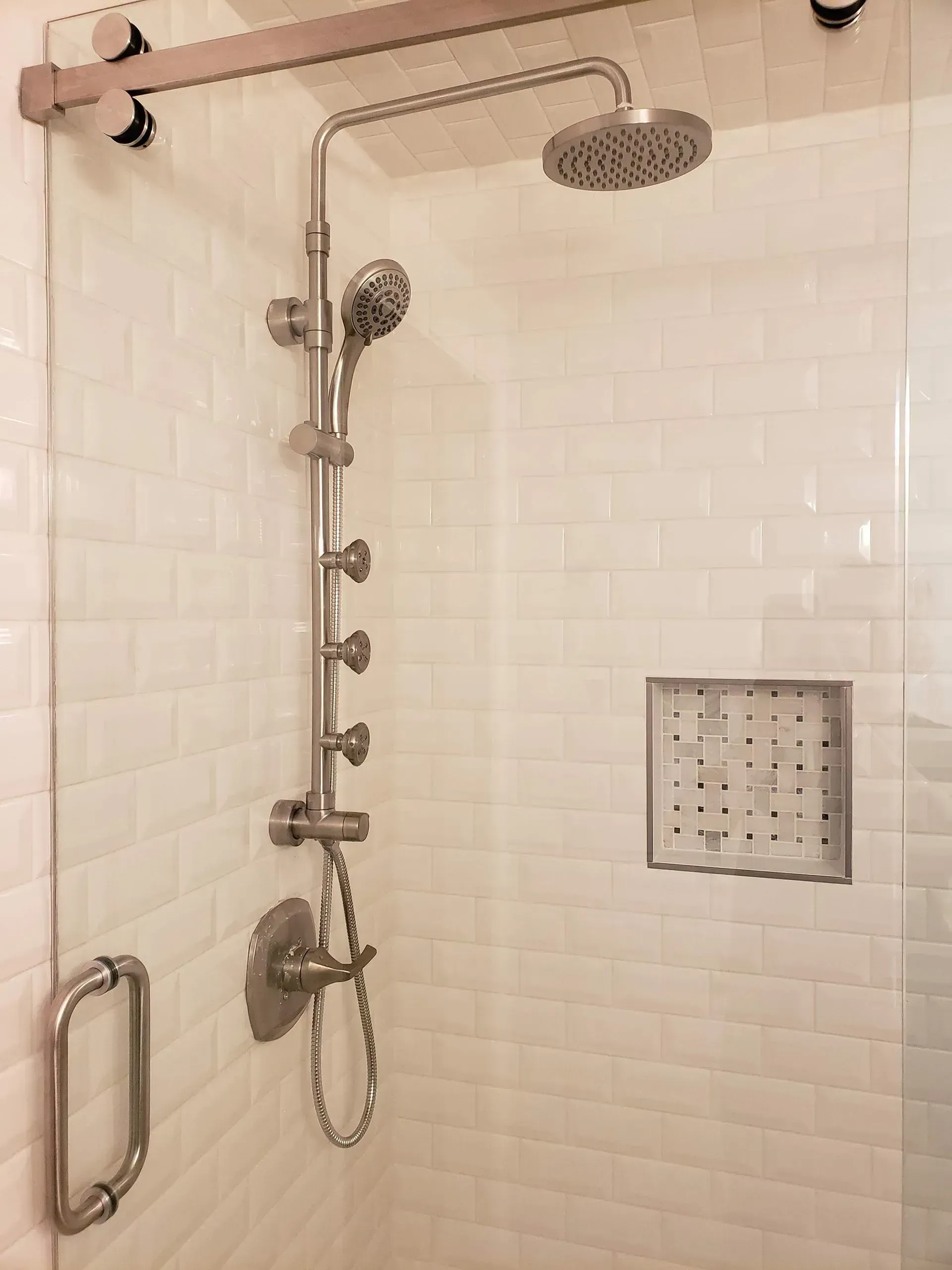 Accessible shower with grab bar, handheld and rain showerheads, and tiled walls