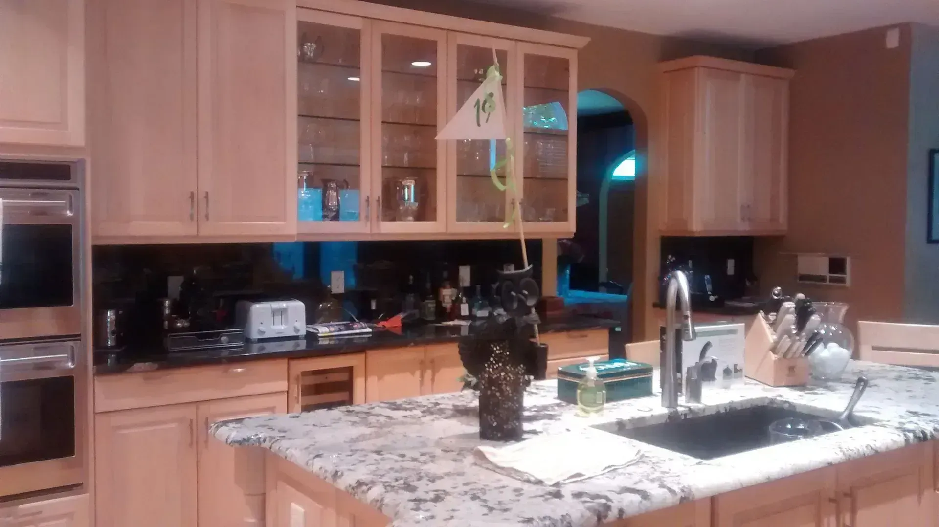 Modern kitchen with wooden cabinets, granite island, and sink under warm lighting