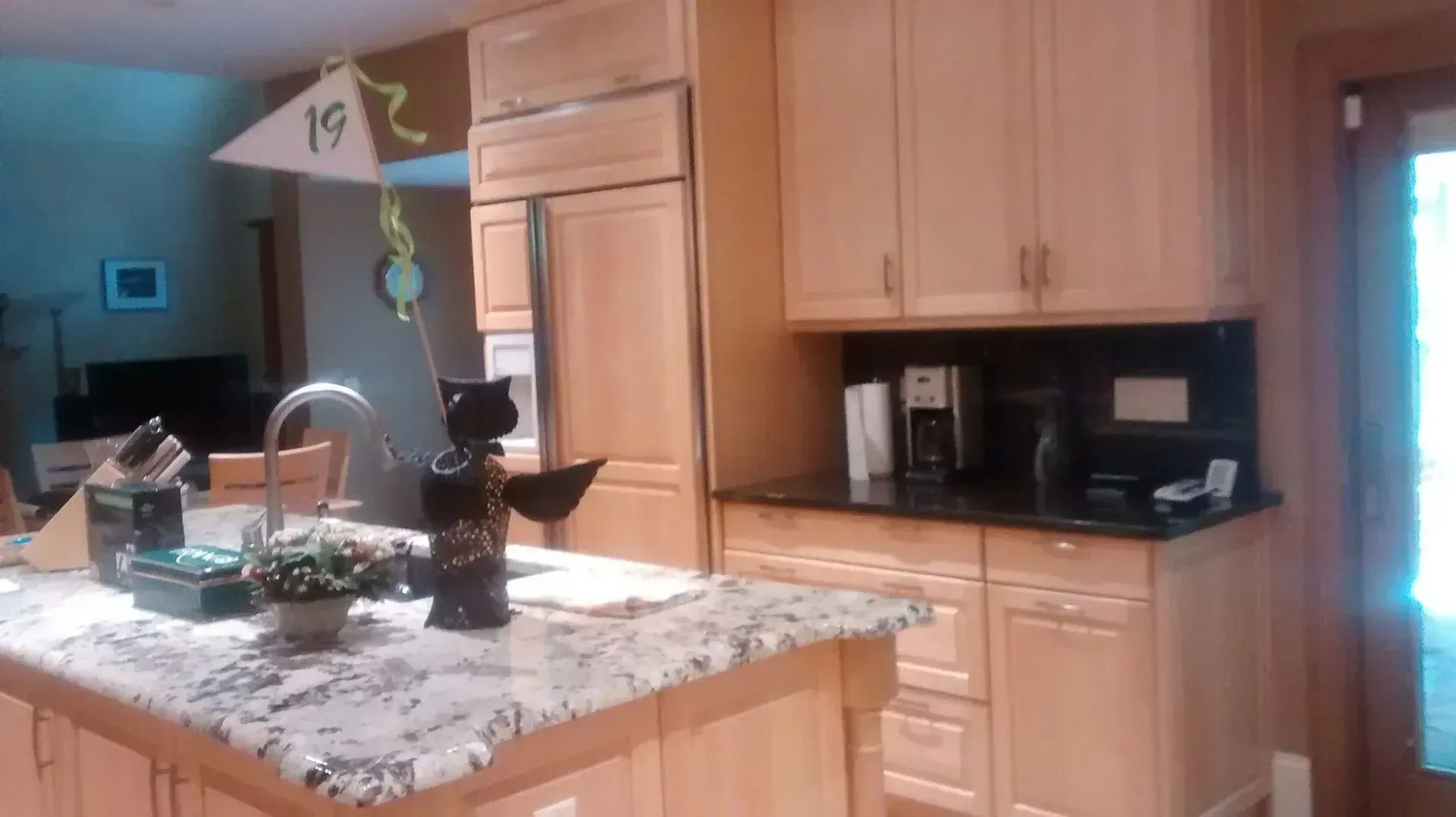 Kitchen with granite island, wooden cabinets, sink, and a bright window on the right.