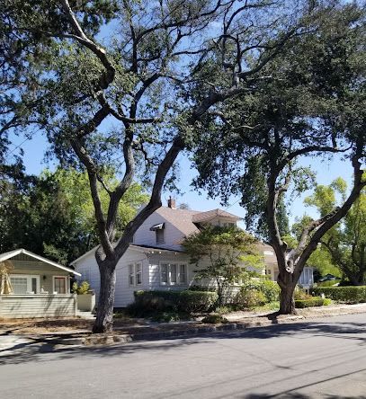 A white house is surrounded by trees on a sunny day.