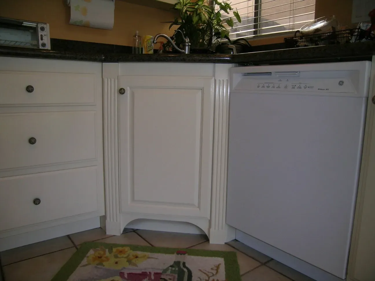 A kitchen with white cabinets and a white dishwasher