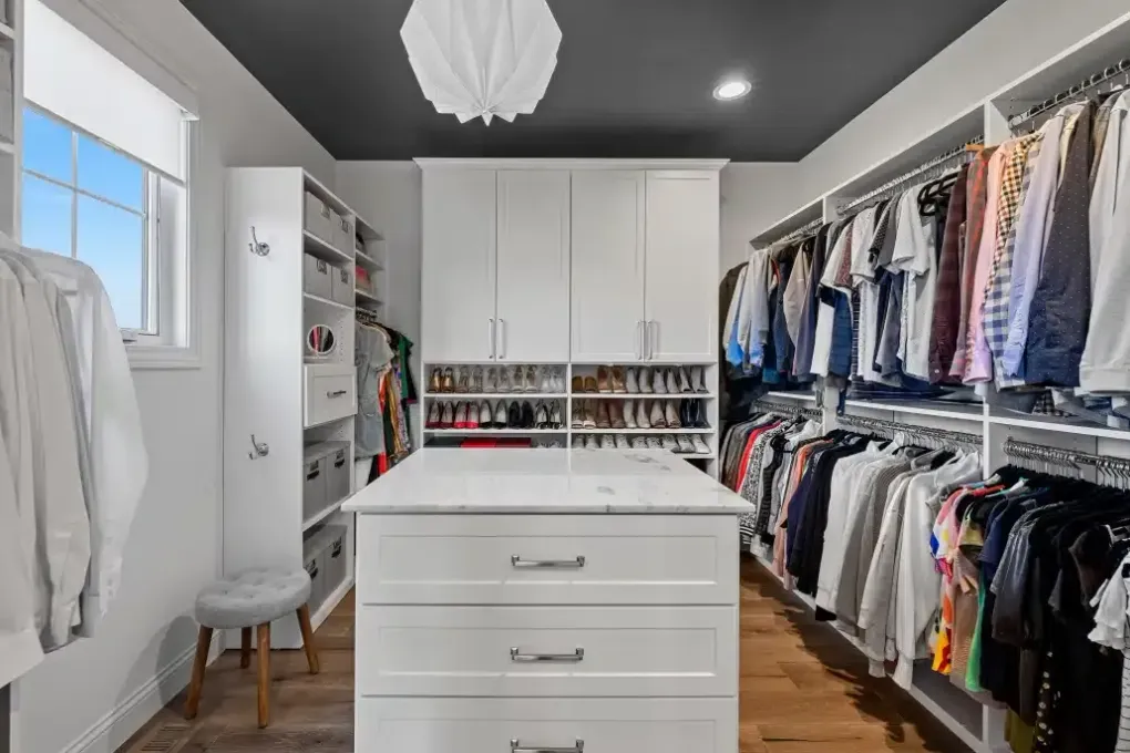 A walk in closet filled with lots of clothes and shoes.