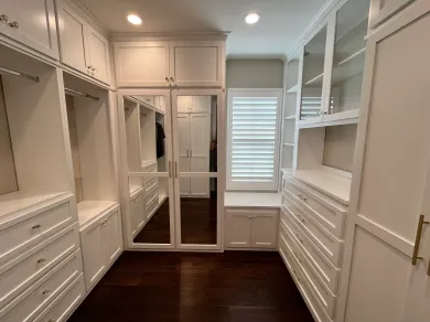 A walk in closet with lots of white cabinets and drawers