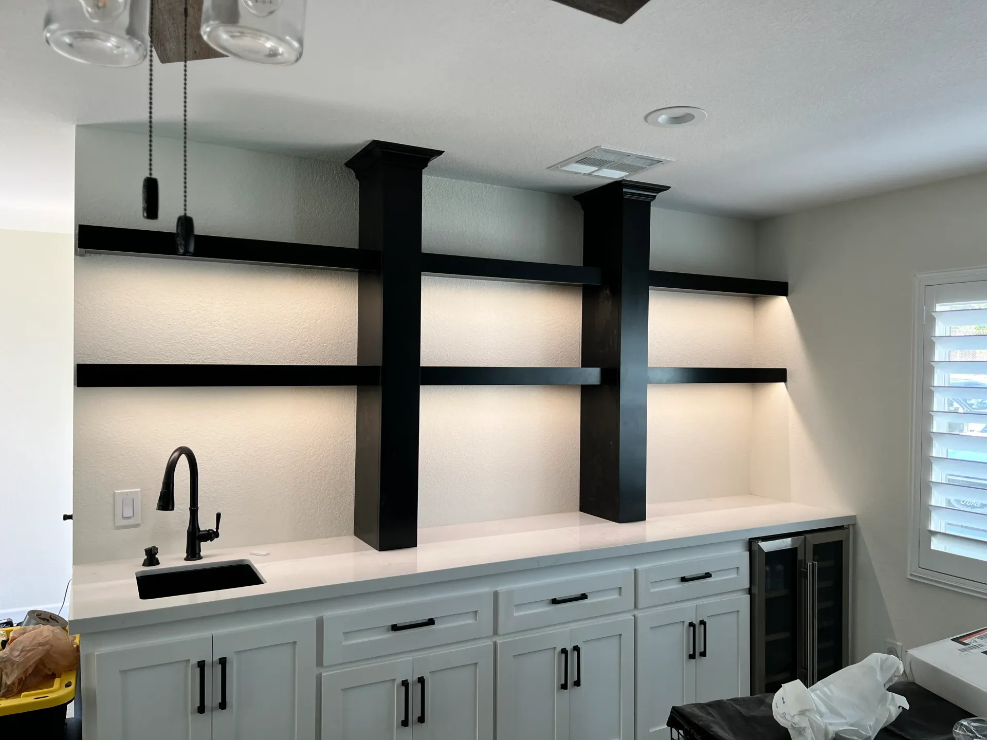 A kitchen with white cabinets and black shelves and a sink.