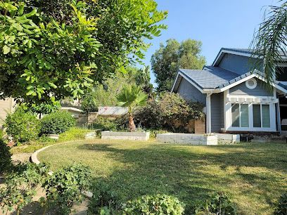 A house with a large lawn in front of it surrounded by trees and bushes.