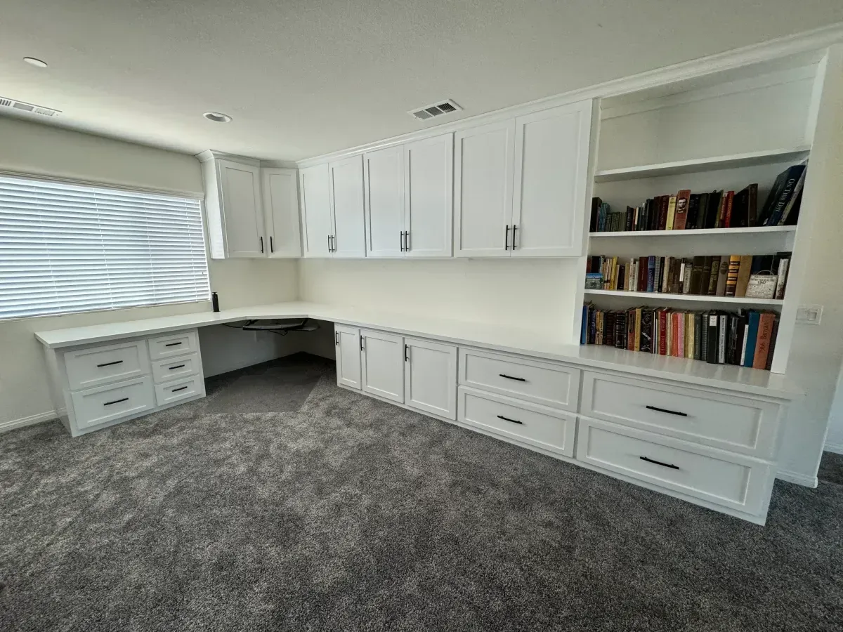 A room with white cabinets and shelves filled with books.