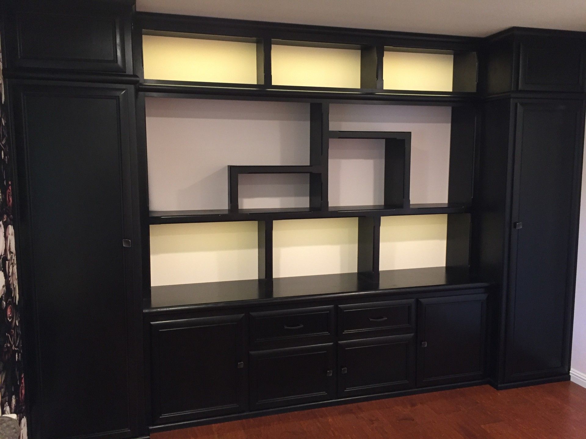 A room with black cabinets and shelves and a wooden floor