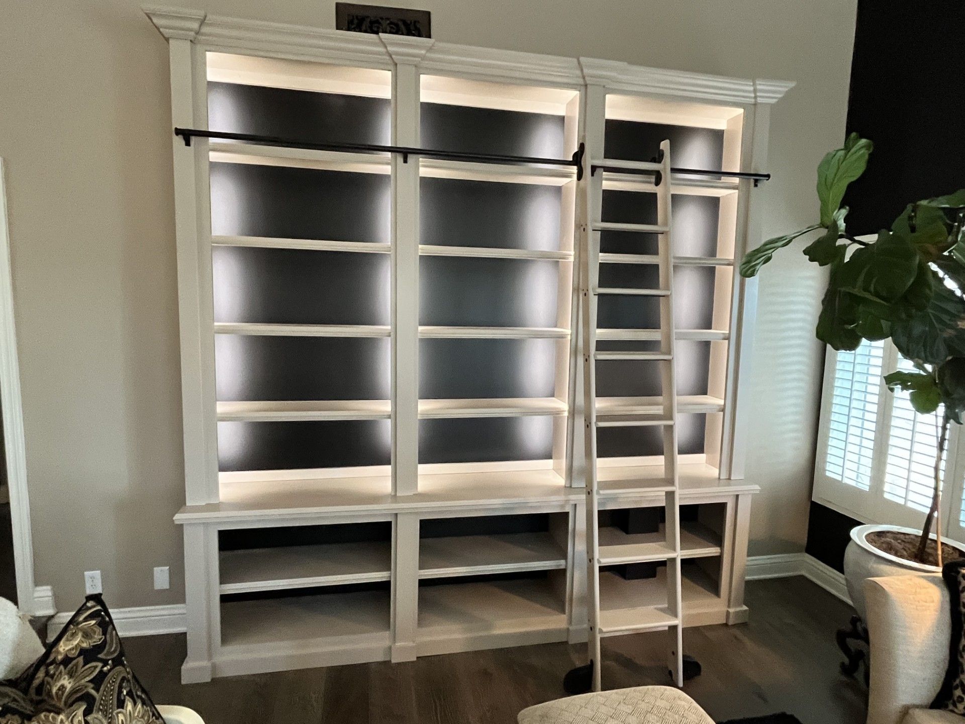 A living room with a large bookshelf and a ladder.