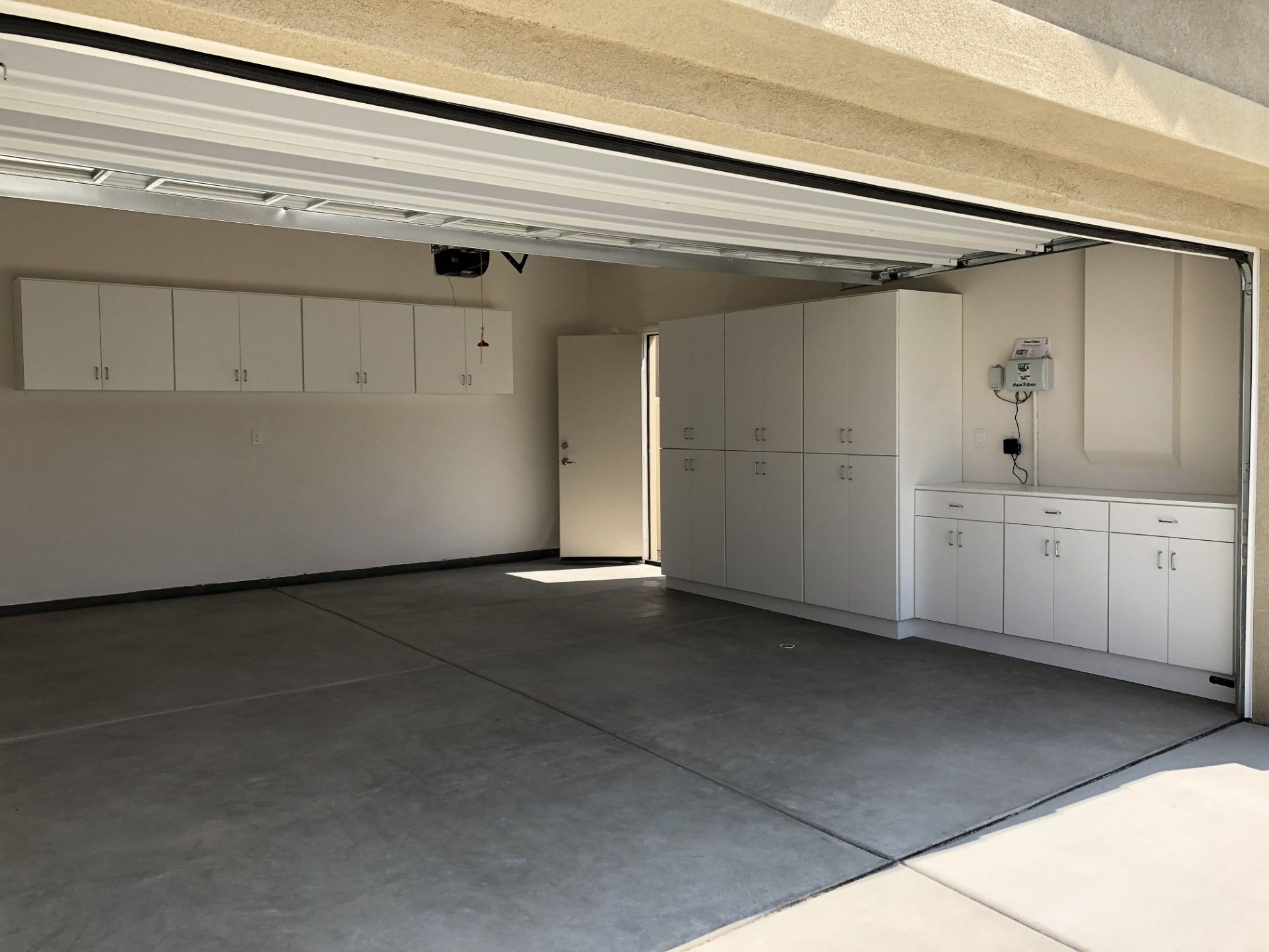 An empty garage with white cabinets and a clock on the wall