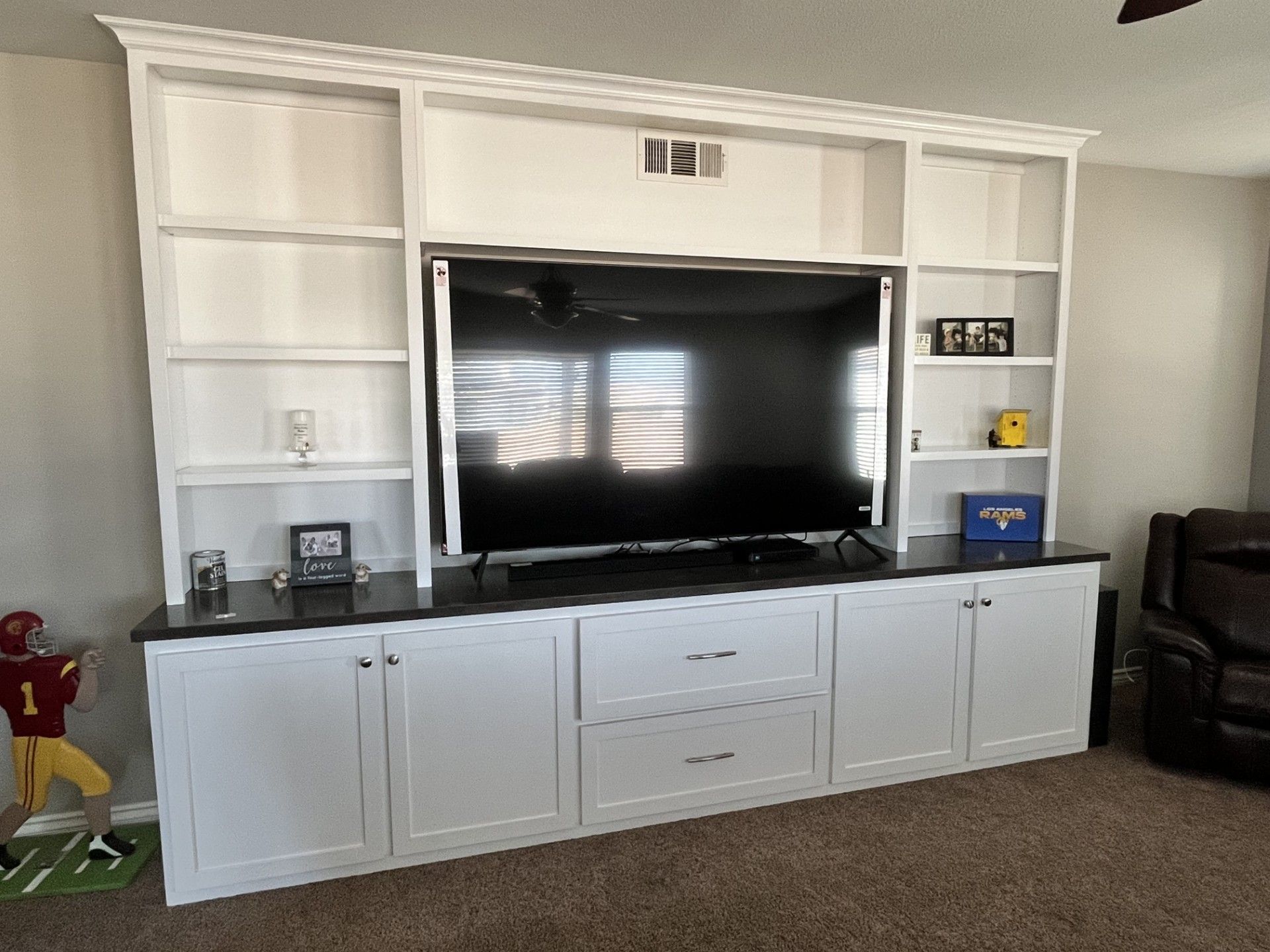 A living room with a large entertainment center and a flat screen tv.