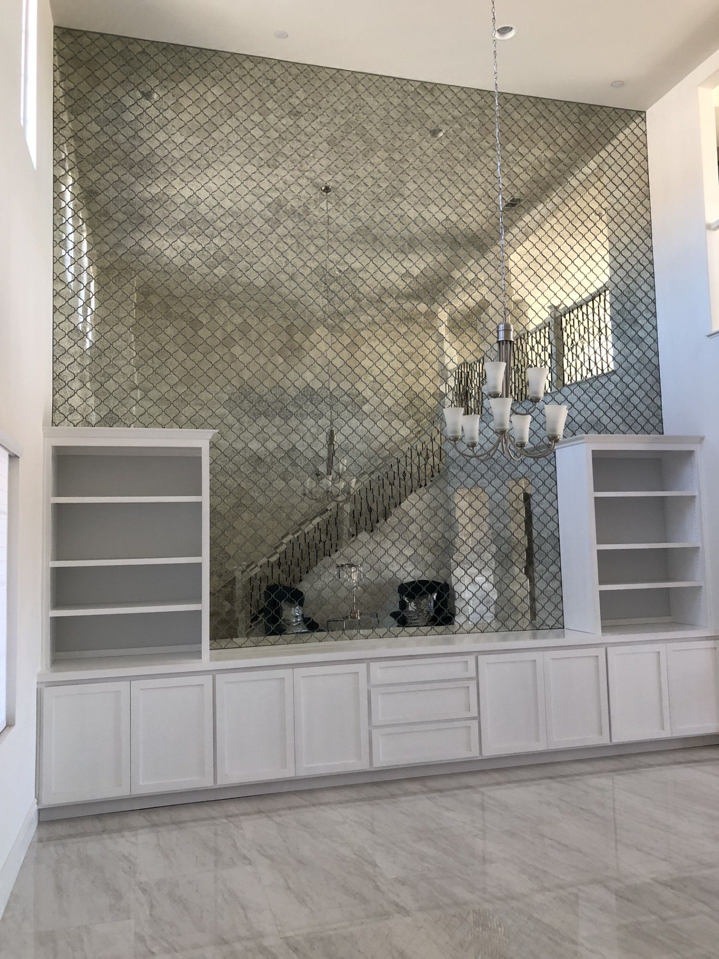 A living room with a large mirrored wall and a chandelier.