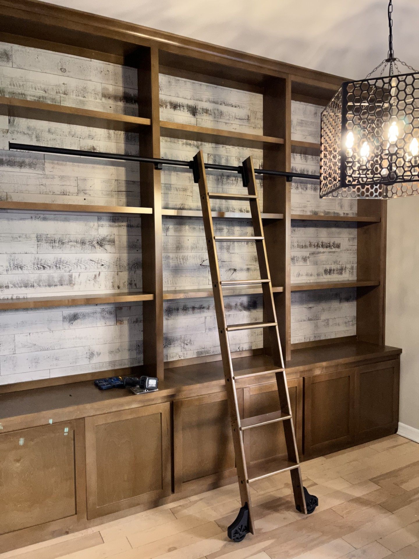 A wooden ladder is sitting in front of a wall of shelves.