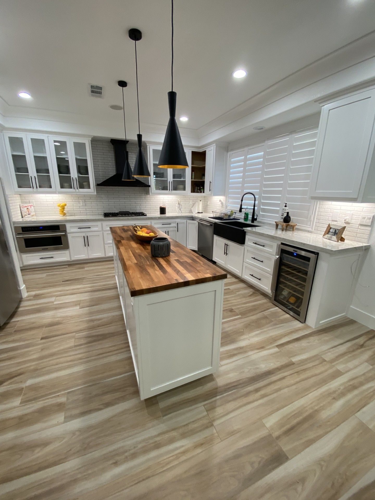 A kitchen with white cabinets and a wooden counter top.