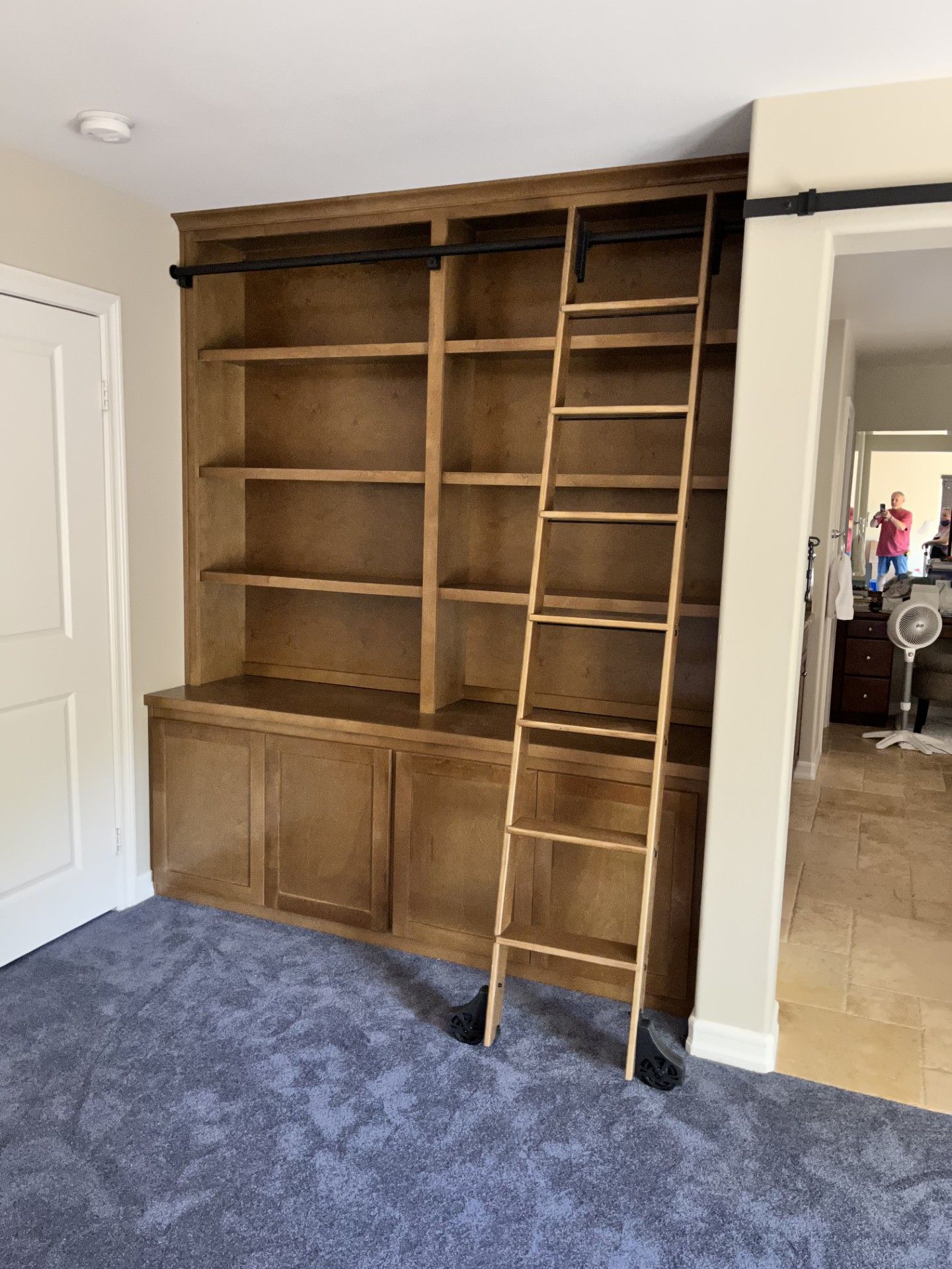 A wooden ladder is attached to a bookshelf in a room.