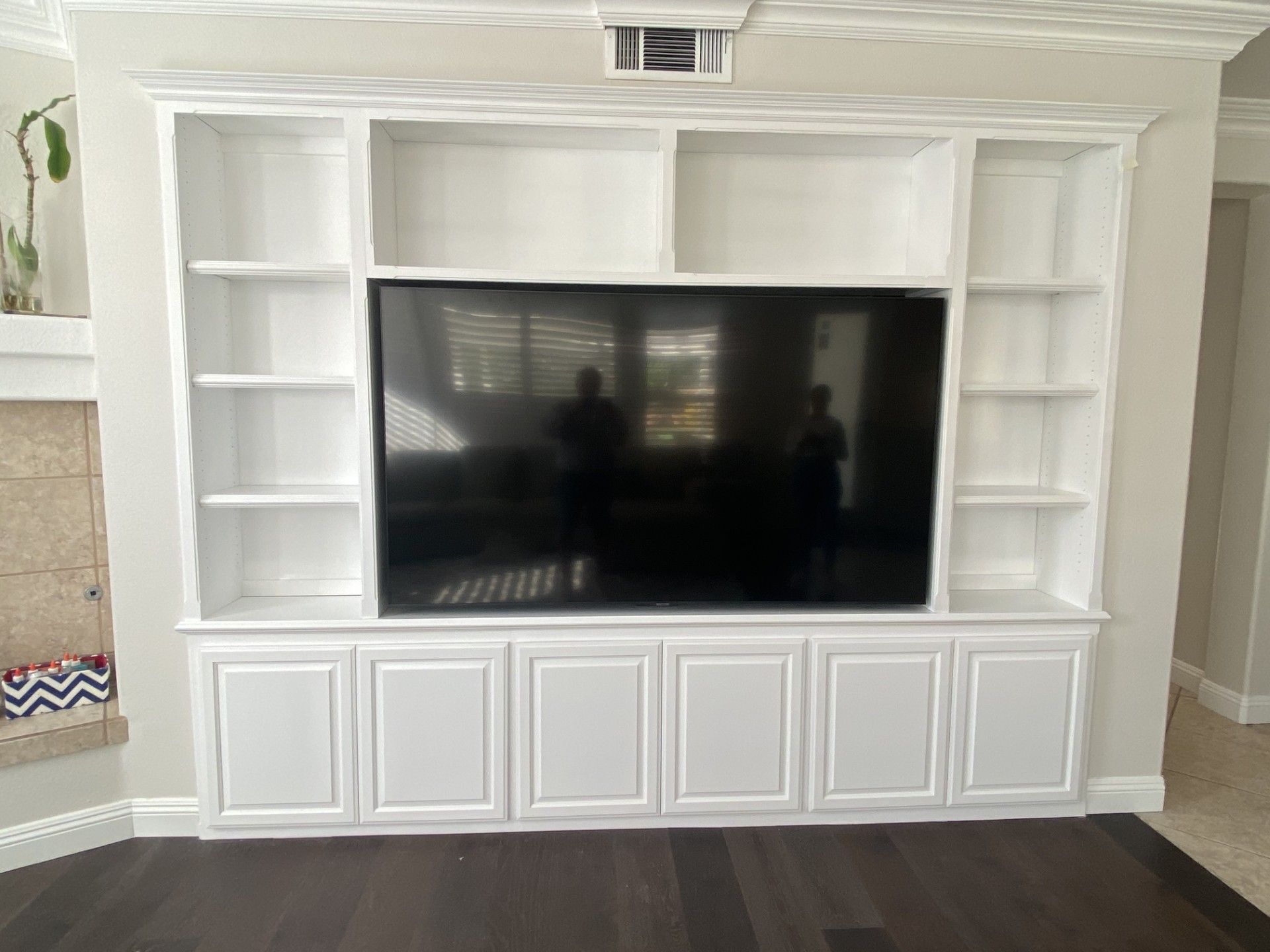 A living room with white shelves and a flat screen tv