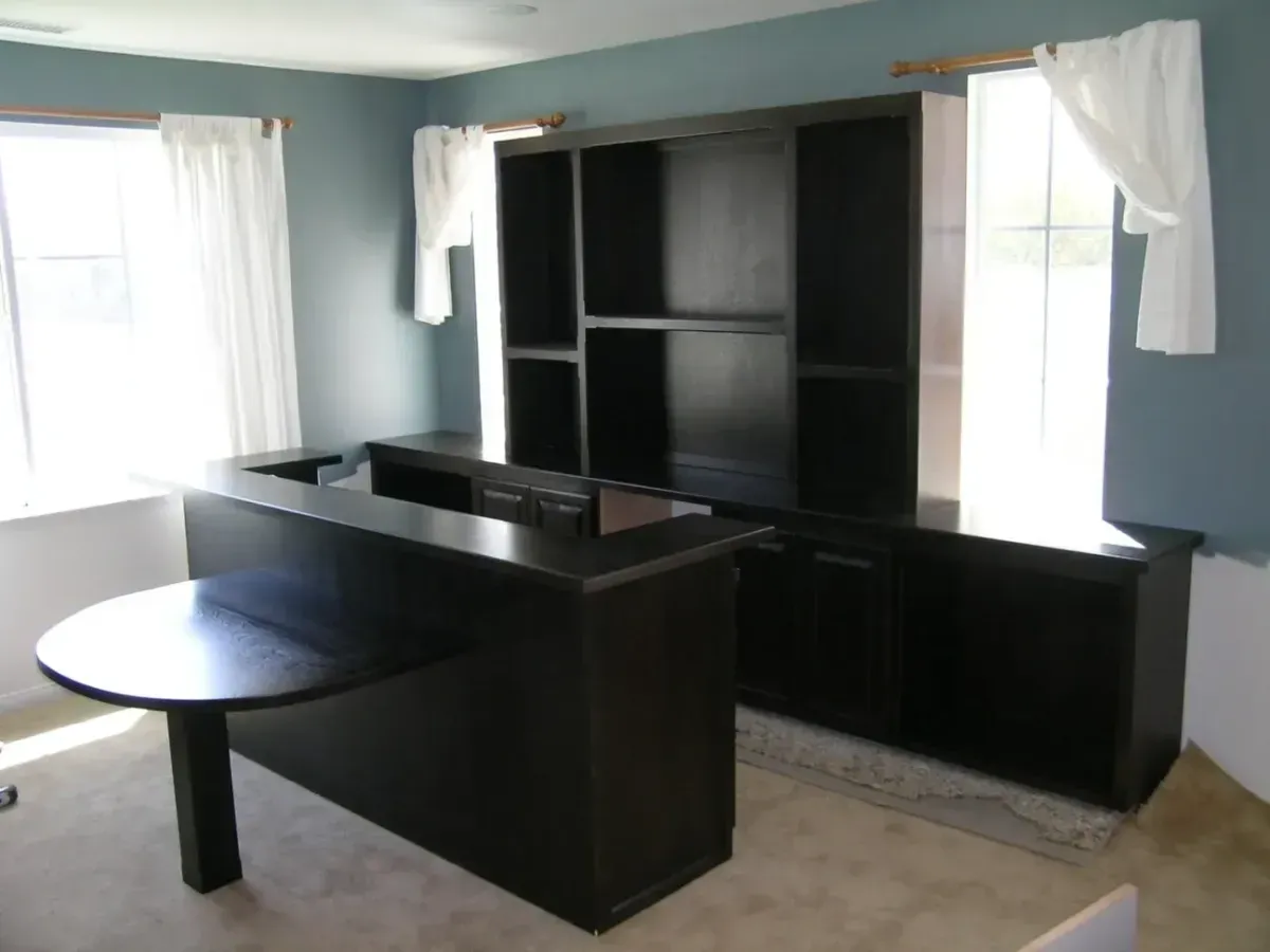 A corner of a room with a desk and shelves