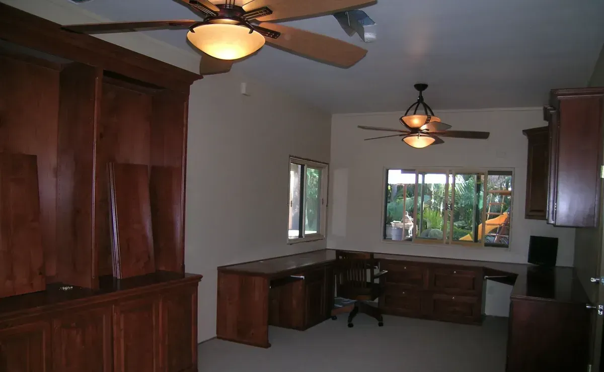 A room with a desk and a ceiling fan