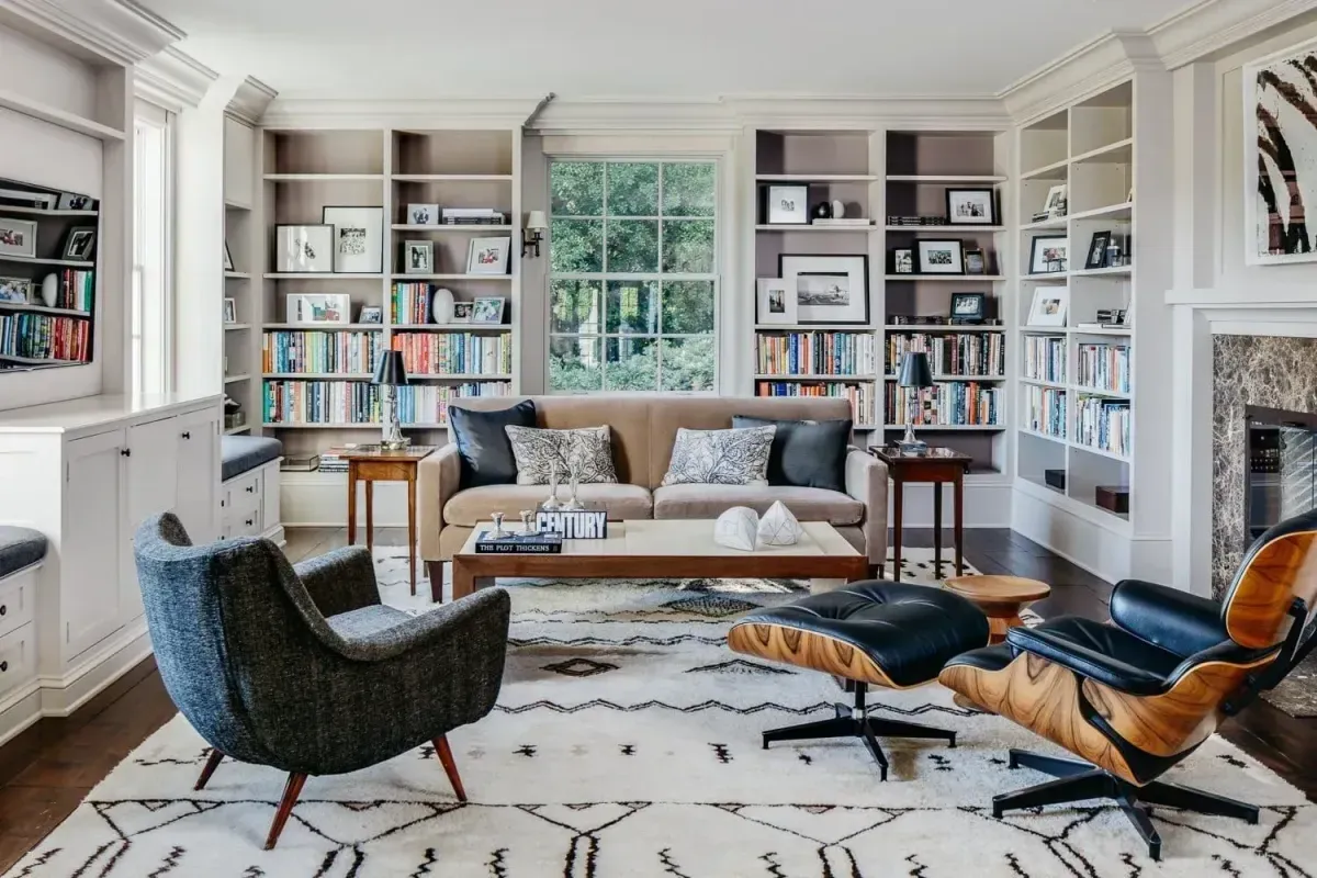 A living room with a couch , chairs , coffee table and bookshelves.