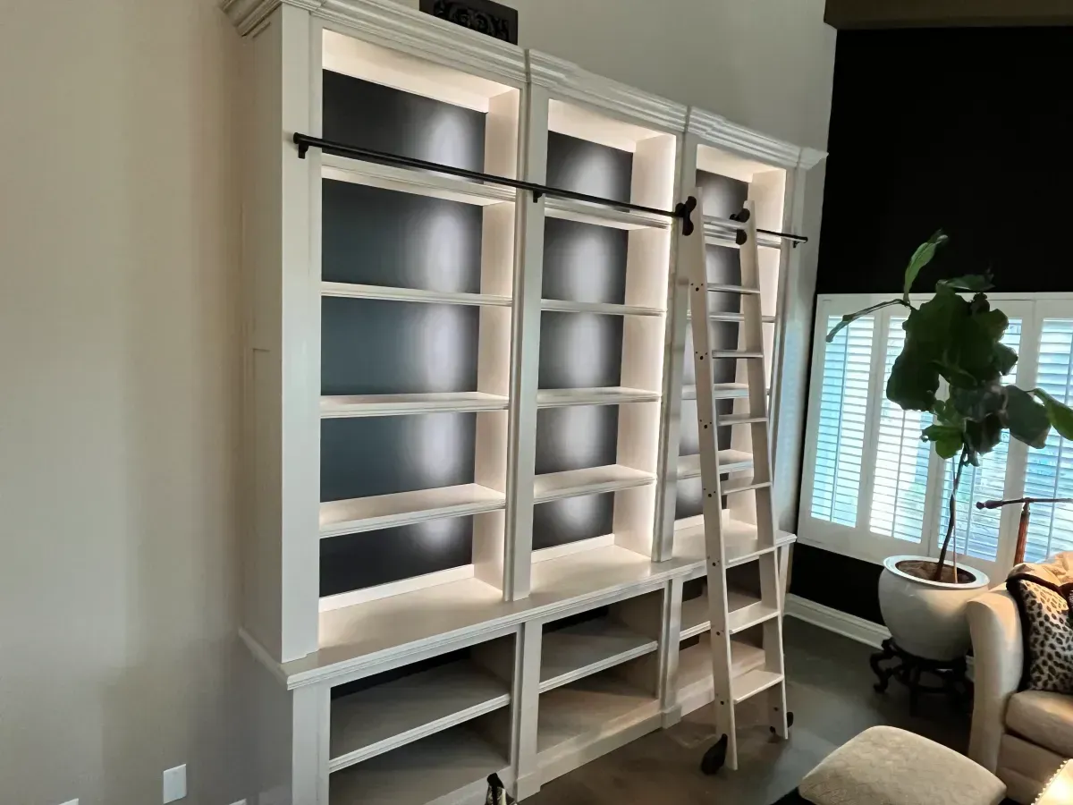 A living room with a lot of shelves and a ladder.