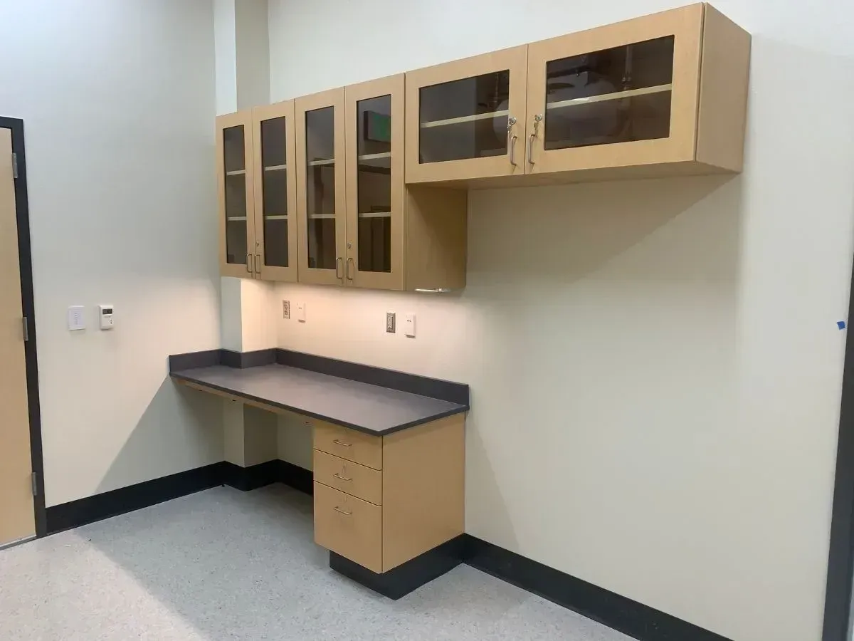 A room with a desk and cabinets on the wall.