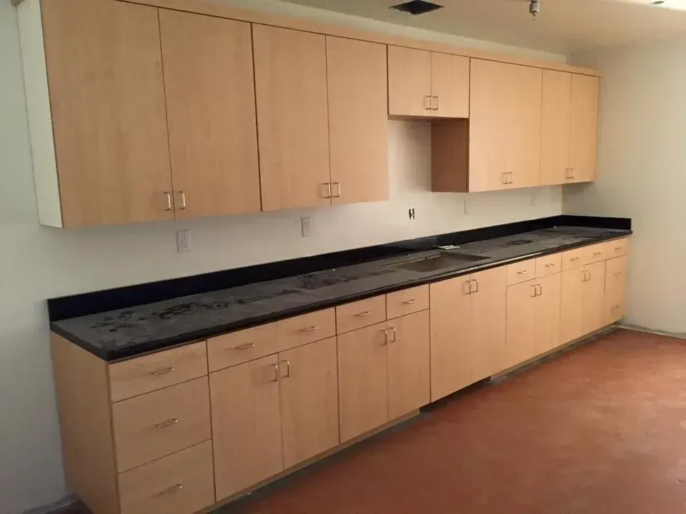 A kitchen with wooden cabinets and black counter tops