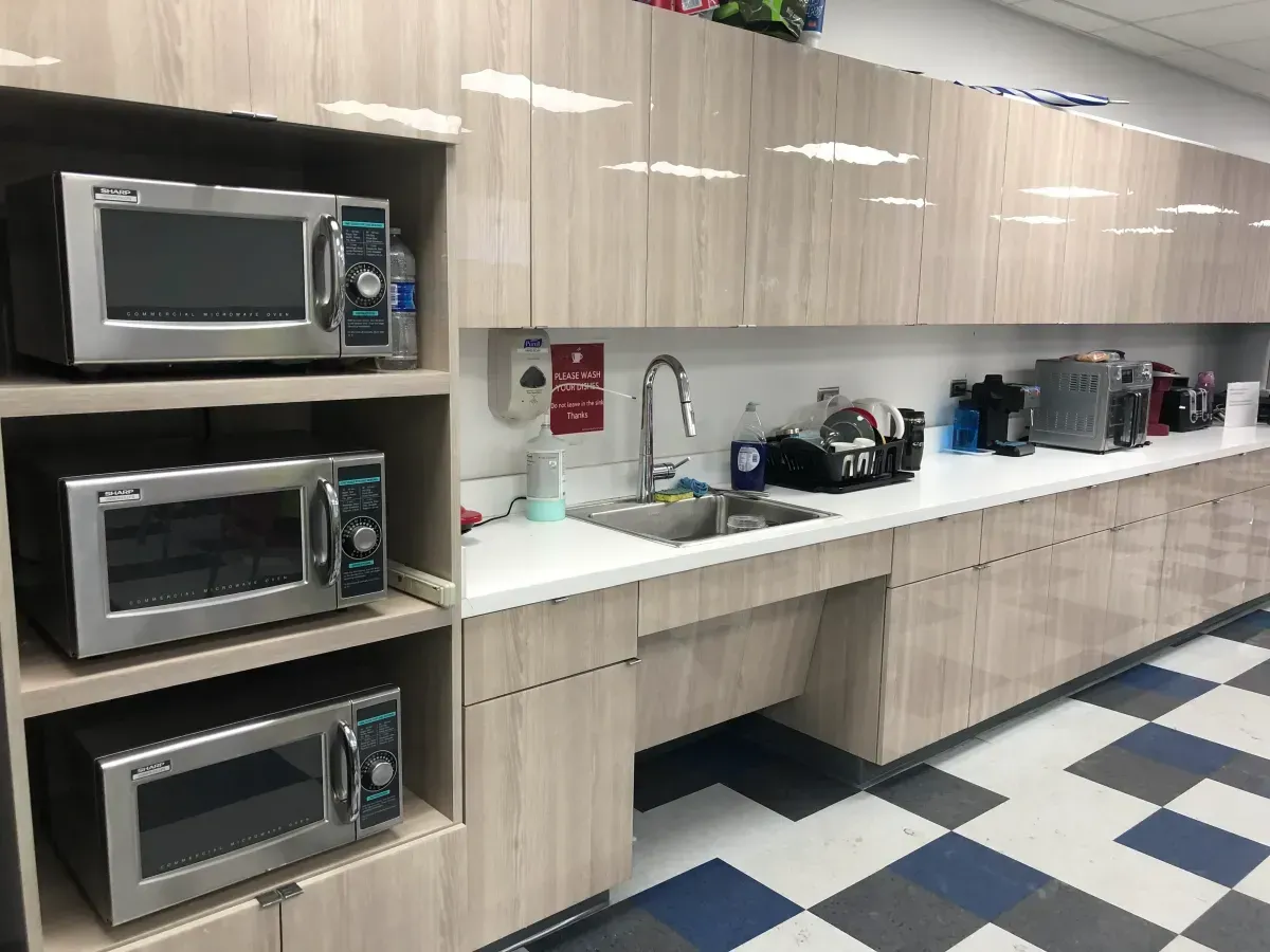 A kitchen with a sink , microwave ovens , and a checkered floor.