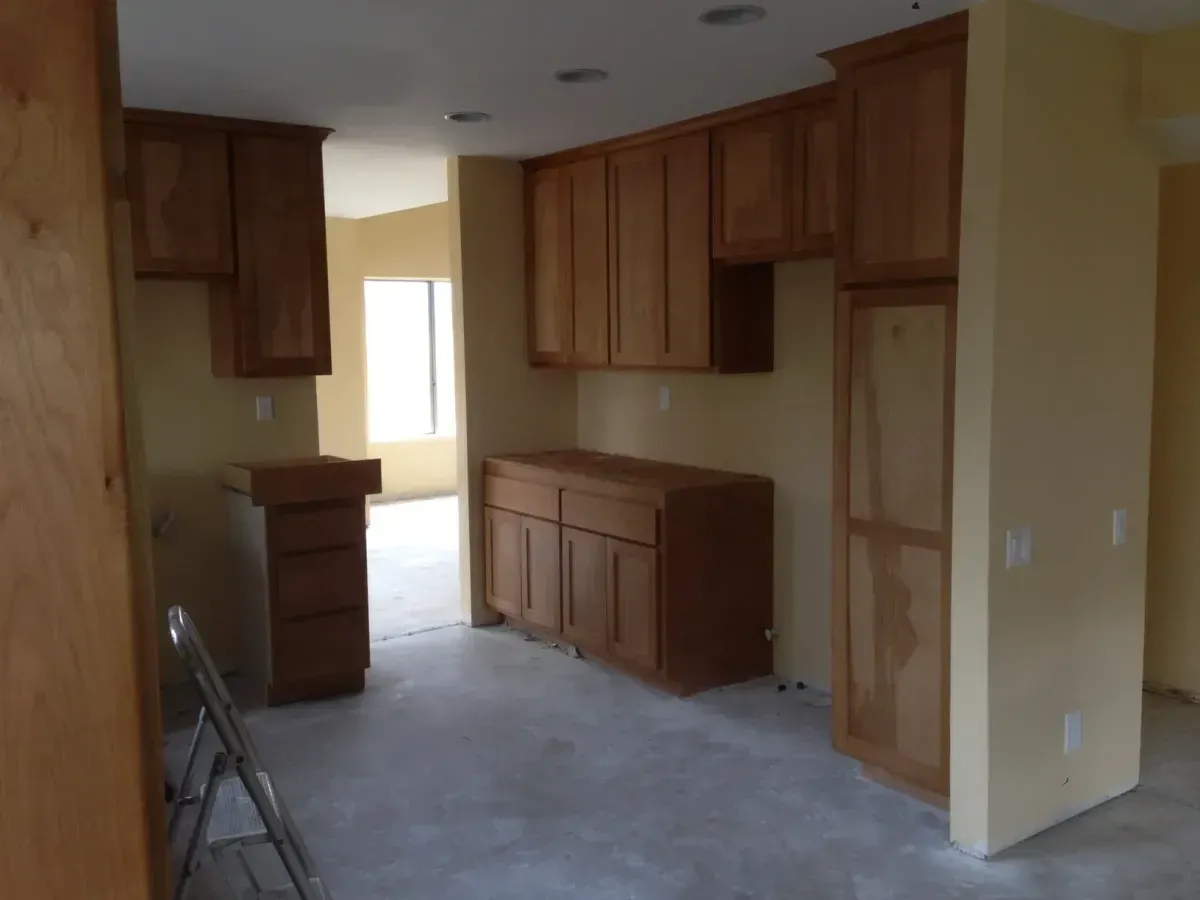 An empty kitchen with wooden cabinets and a ladder