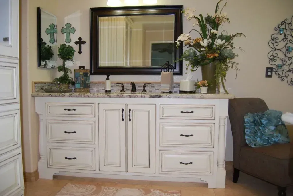 A bathroom with white cabinets and a large mirror