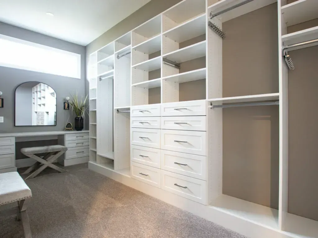 A walk in closet with lots of shelves and drawers and a vanity.