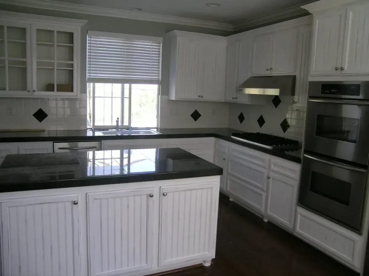 A kitchen with white cabinets and black counter tops
