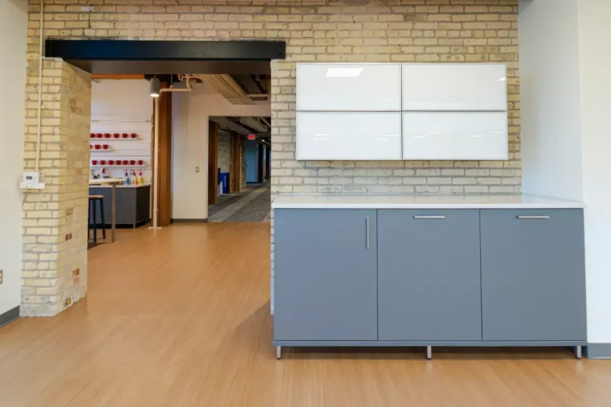 A kitchen with a brick wall and gray cabinets
