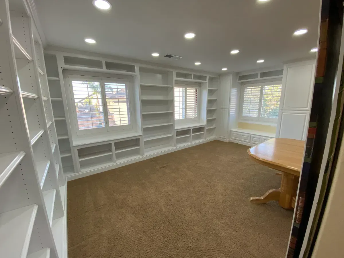 A large empty room with lots of shelves and a table.
