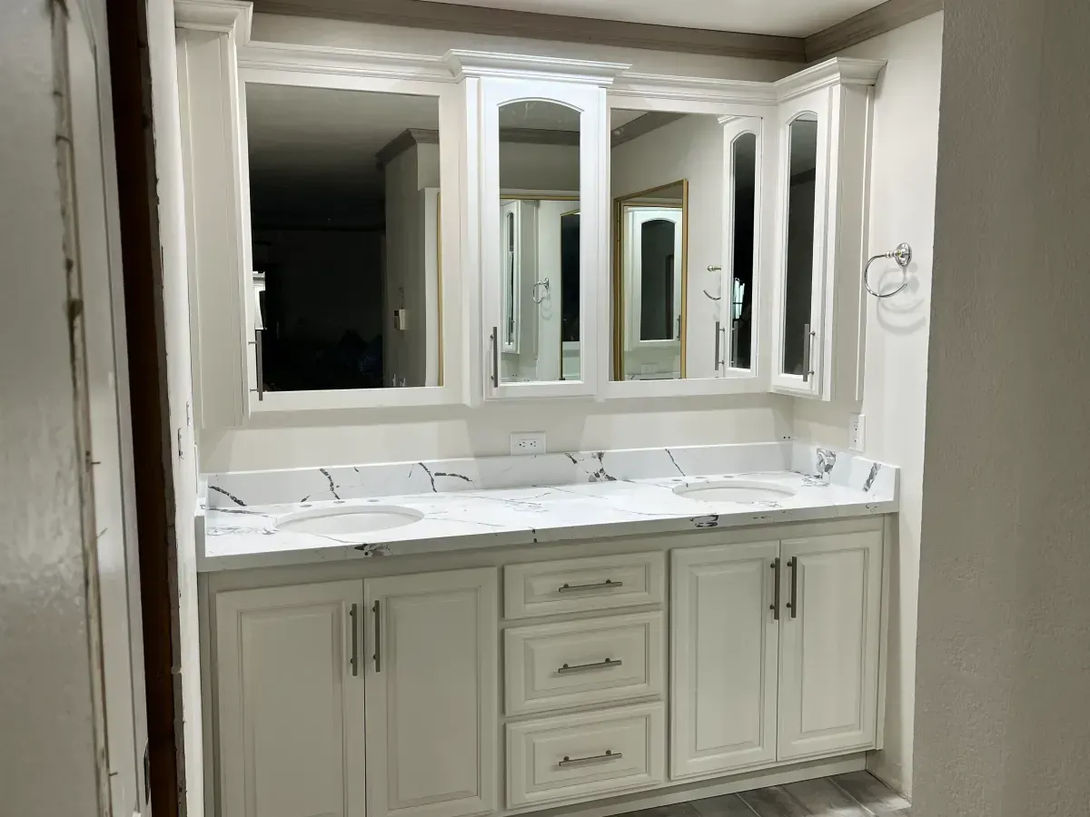 A bathroom with two sinks , two mirrors , and white cabinets.