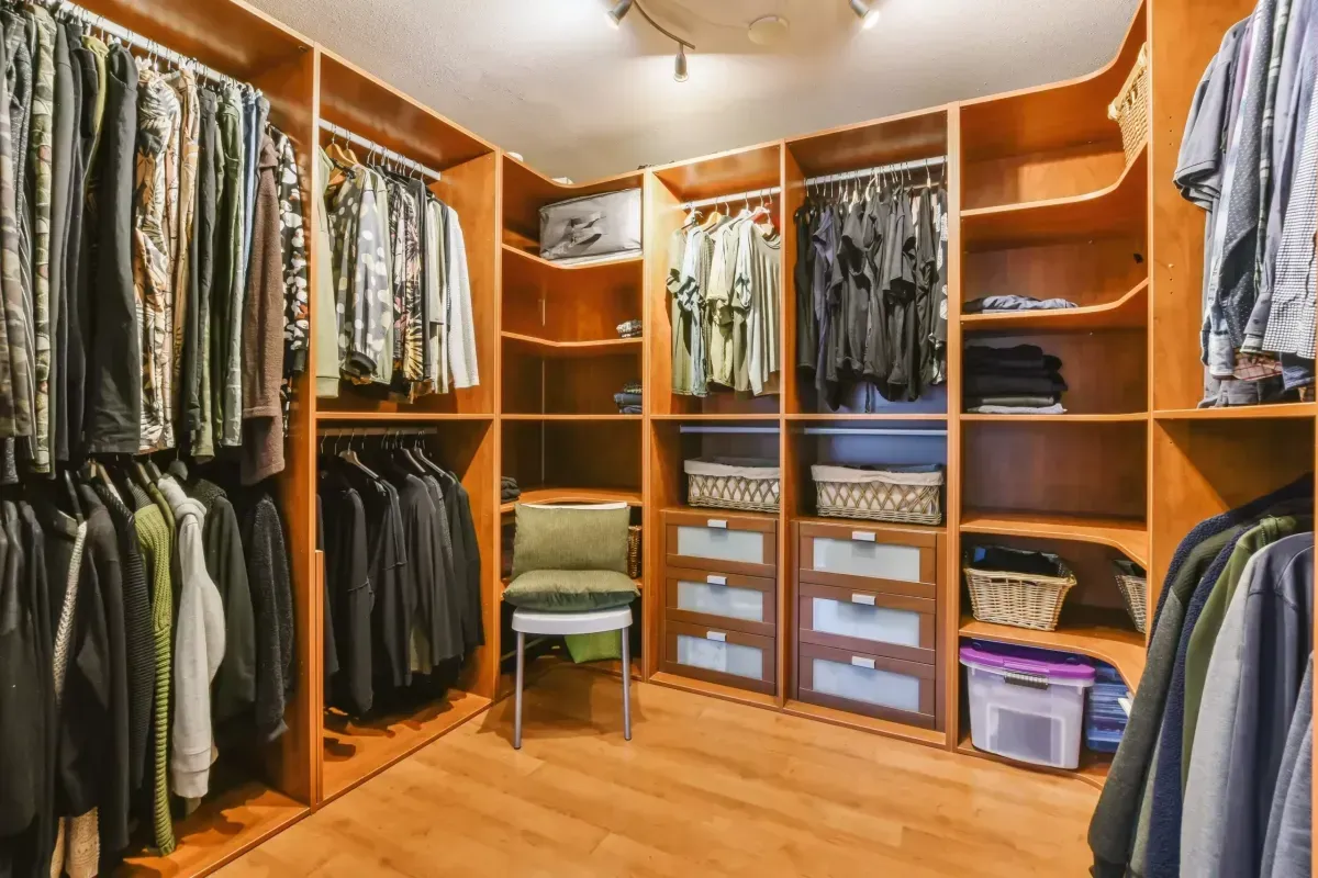 A walk in closet filled with lots of clothes and a chair.