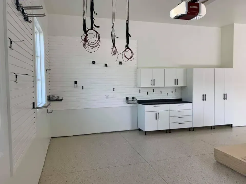 An empty garage with white cabinets and a garage door opener.