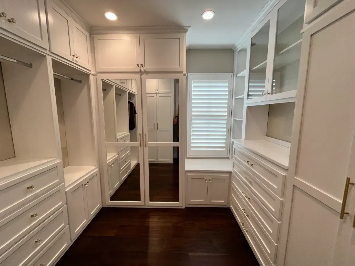 A walk in closet with lots of white cabinets and drawers