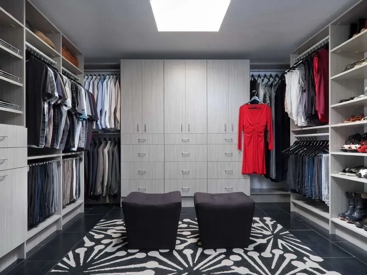 A walk in closet with a red dress hanging on the wall