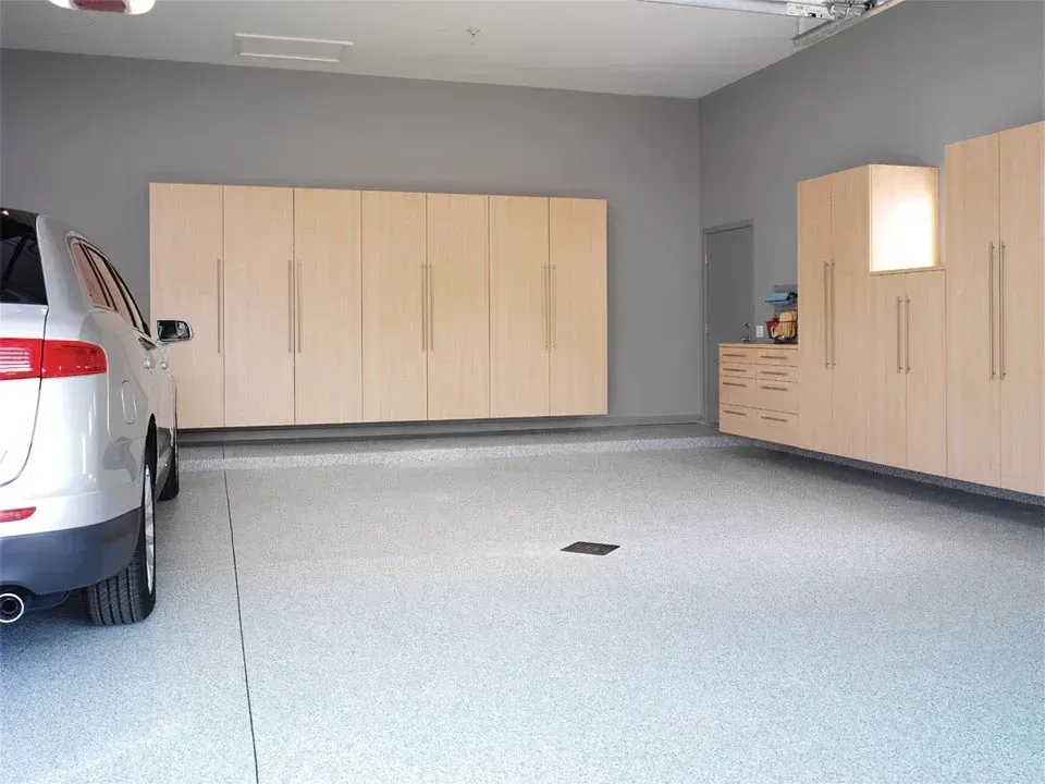 A car is parked in a garage with lots of cabinets.